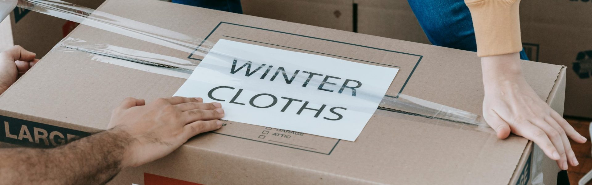 Caja siendo precintada, con las palabras "Winter Clothes" escritas en la caja.